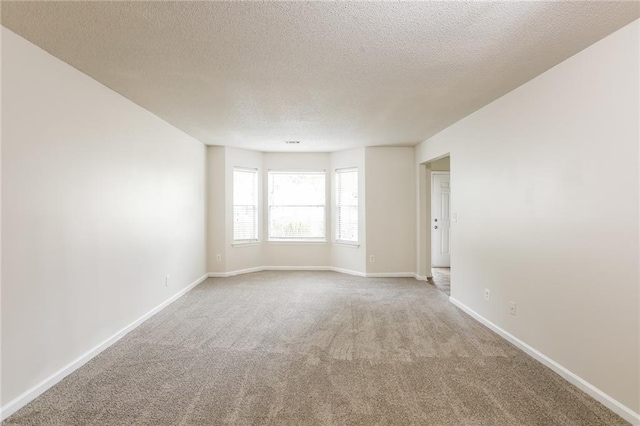 carpeted empty room with a textured ceiling