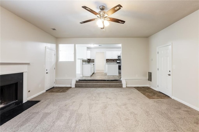 unfurnished living room featuring ceiling fan and light colored carpet