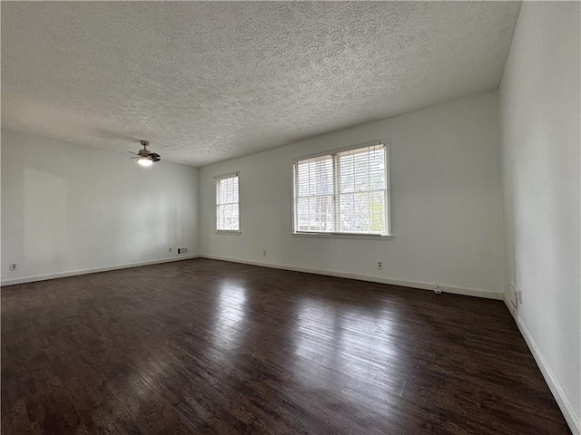 spare room featuring a textured ceiling, baseboards, ceiling fan, and dark wood-style flooring