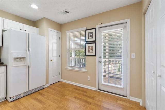 entryway with baseboards, visible vents, and light wood-type flooring