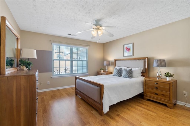 bedroom featuring visible vents, baseboards, a textured ceiling, and light wood-style flooring