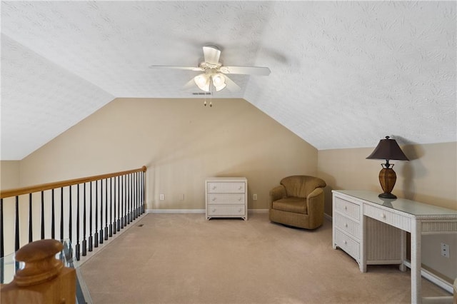 living area featuring a ceiling fan, baseboards, lofted ceiling, a textured ceiling, and light colored carpet