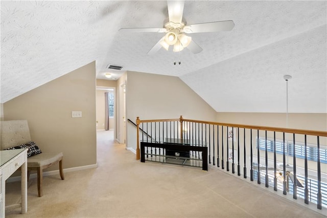 interior space with visible vents, carpet flooring, a textured ceiling, and lofted ceiling