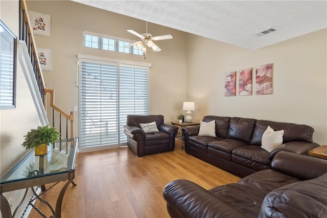 living area with visible vents, a textured ceiling, wood finished floors, stairway, and ceiling fan