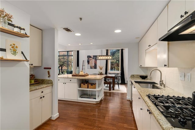 kitchen with visible vents, open shelves, under cabinet range hood, black gas stovetop, and a sink