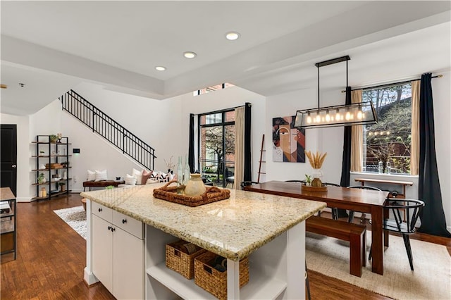 kitchen featuring light stone counters, a kitchen island, open shelves, dark wood-style flooring, and white cabinetry