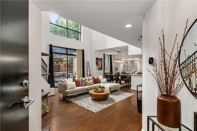 living room with stairs, a high ceiling, and wood finished floors