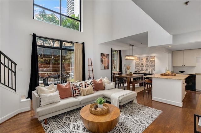 living room with baseboards, stairs, a high ceiling, and dark wood-style flooring