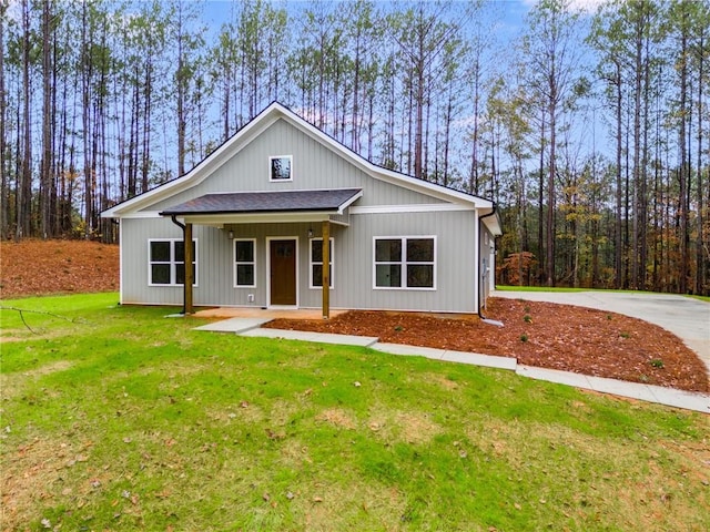 modern farmhouse style home with covered porch, roof with shingles, and a front yard