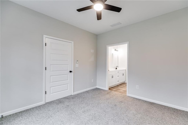 unfurnished bedroom featuring light carpet, a sink, visible vents, baseboards, and ensuite bath