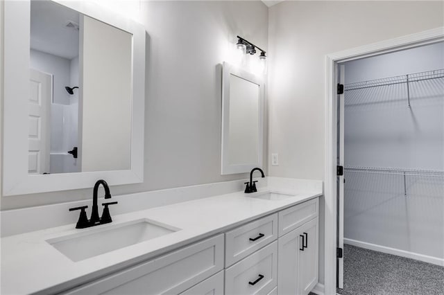 full bathroom featuring double vanity, a spacious closet, and a sink