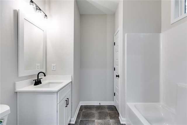 bathroom with toilet, stone finish floor, baseboards, and vanity