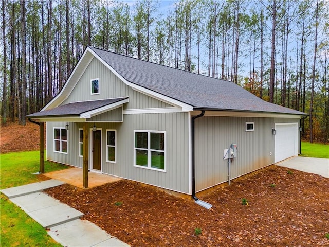 view of front of home with an attached garage, a shingled roof, and a front yard