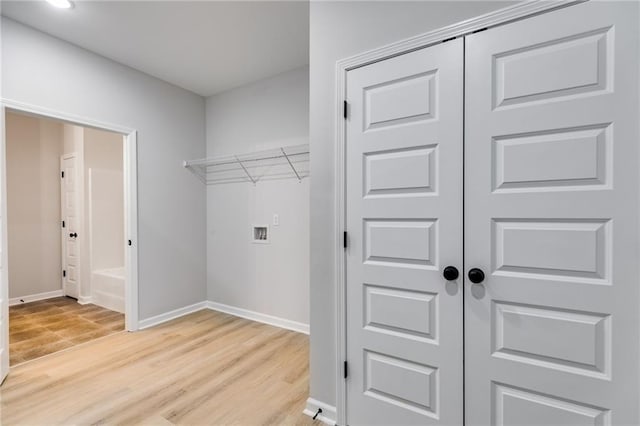 clothes washing area with laundry area, light wood-style flooring, hookup for a washing machine, and baseboards