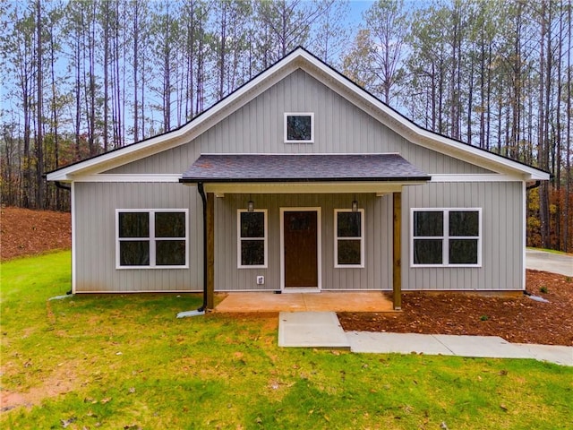 modern farmhouse with a porch, a front lawn, and roof with shingles