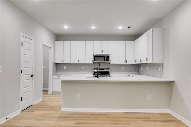 kitchen featuring light countertops, appliances with stainless steel finishes, a sink, and light wood-style floors