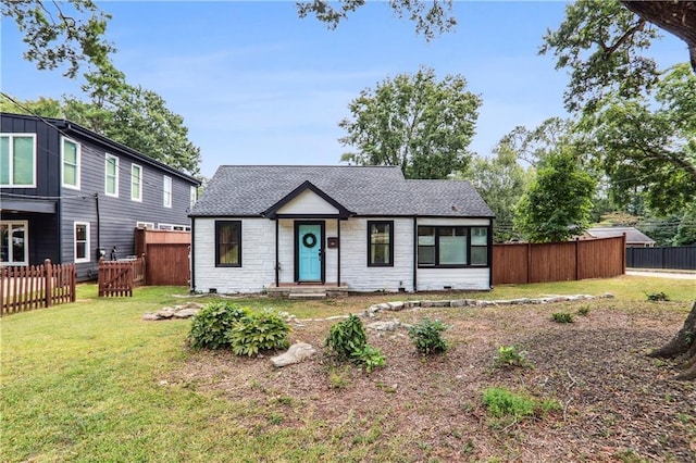 view of front of home with a front lawn, fence, stone siding, and roof with shingles