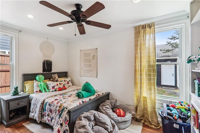 bedroom featuring crown molding, multiple windows, and wood finished floors