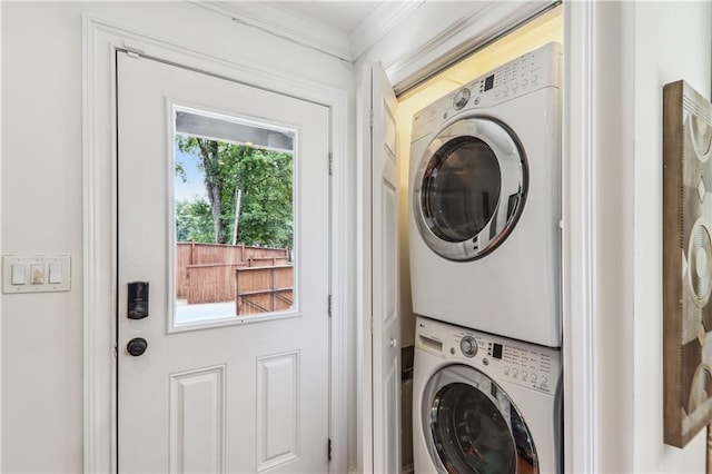 laundry area featuring laundry area, stacked washer / drying machine, and ornamental molding