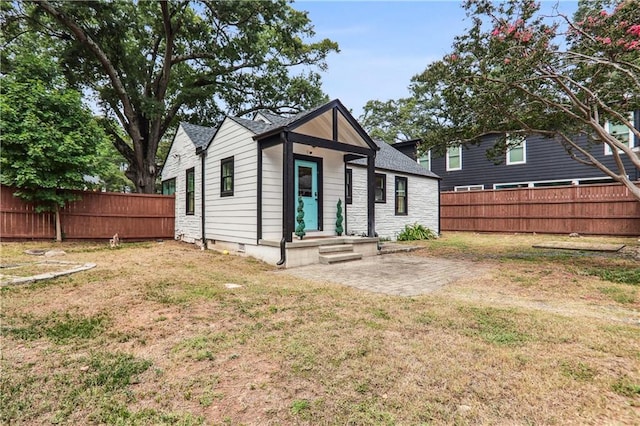 view of front of house featuring crawl space, a patio, a front lawn, and fence