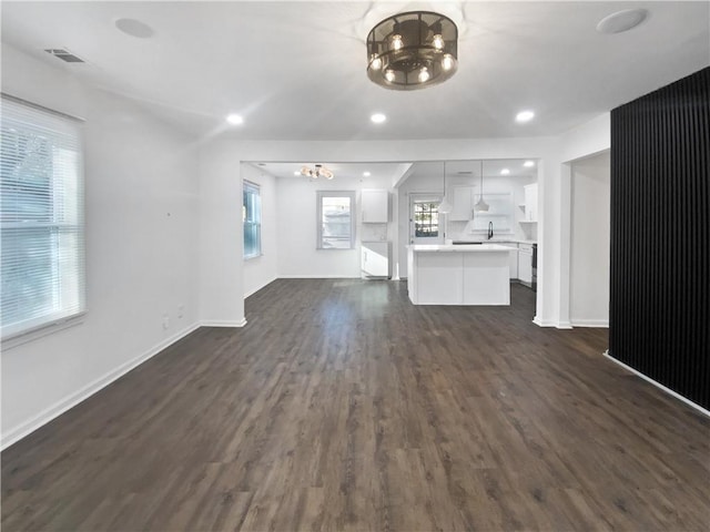 unfurnished living room with dark hardwood / wood-style floors, sink, and an inviting chandelier