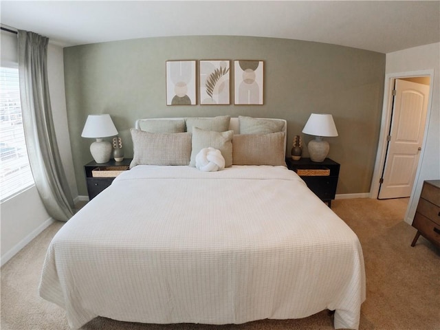 bedroom featuring multiple windows, light carpet, and baseboards