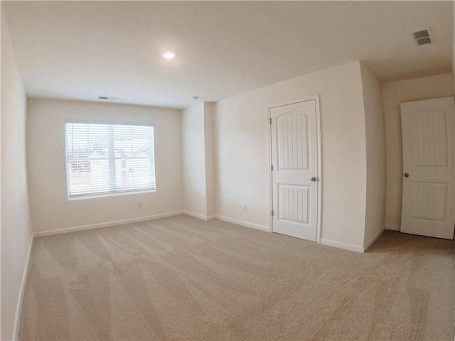 unfurnished room featuring light carpet, visible vents, and baseboards