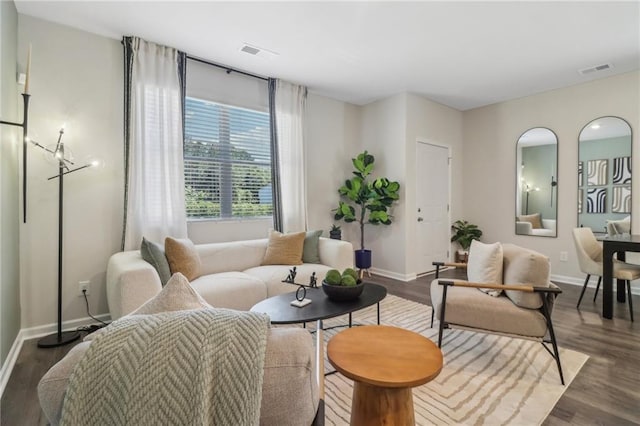 living area with baseboards, visible vents, and wood finished floors