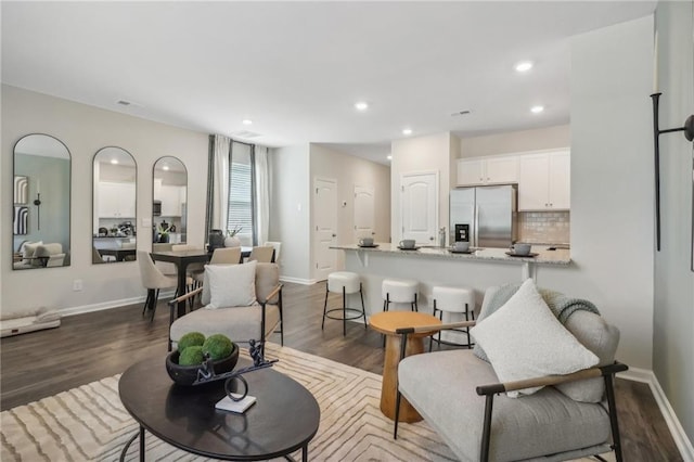 living area featuring baseboards, dark wood finished floors, and recessed lighting