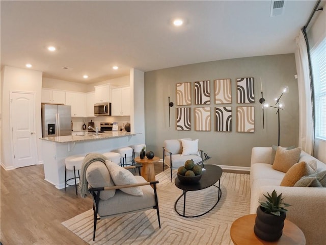 living room with a wealth of natural light, recessed lighting, visible vents, and light wood finished floors