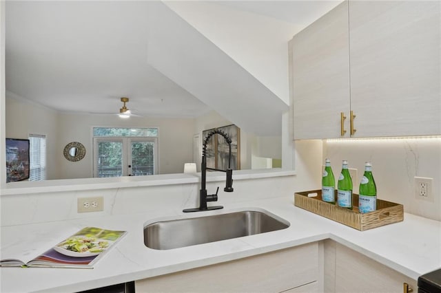 kitchen with ceiling fan, sink, french doors, light stone counters, and kitchen peninsula