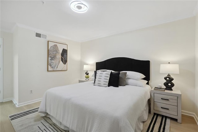 bedroom with ornamental molding and light wood-type flooring