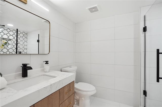 bathroom featuring vanity, tile patterned flooring, toilet, and tile walls