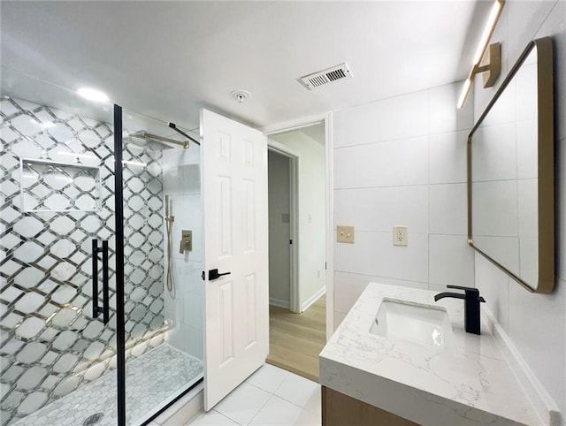 bathroom featuring tile walls, wood-type flooring, vanity, and an enclosed shower