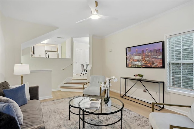 living room featuring ceiling fan, ornamental molding, light hardwood / wood-style flooring, and a healthy amount of sunlight