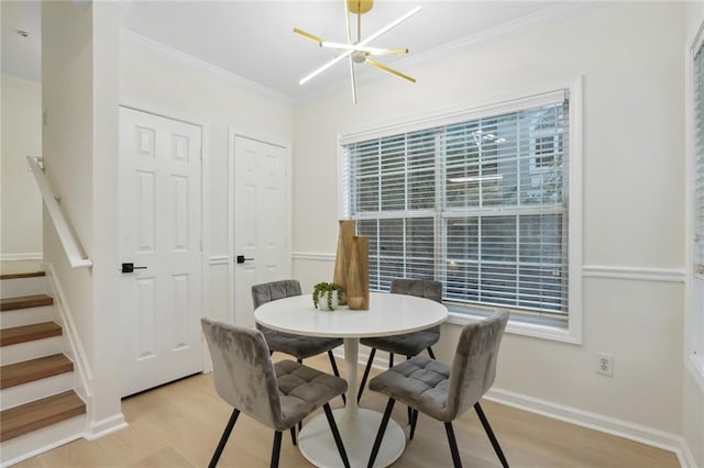 dining room featuring crown molding, light hardwood / wood-style flooring, and a notable chandelier