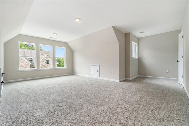 additional living space featuring carpet, visible vents, baseboards, and vaulted ceiling