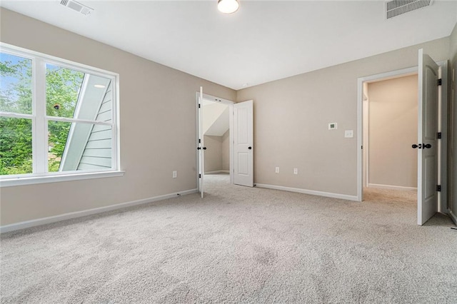 unfurnished bedroom featuring multiple windows, carpet, and visible vents