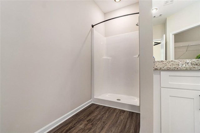 full bathroom with baseboards, a walk in shower, wood finished floors, and vanity