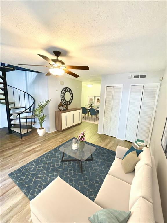 living room with a textured ceiling, hardwood / wood-style flooring, and ceiling fan