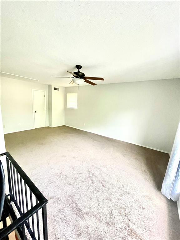 unfurnished bedroom featuring carpet, ceiling fan, and a textured ceiling