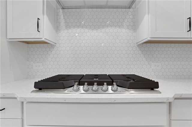 interior details with extractor fan, tasteful backsplash, stainless steel gas stovetop, and white cabinets