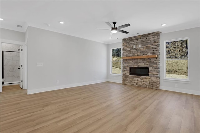 unfurnished living room featuring light wood-style flooring, baseboards, a ceiling fan, and a stone fireplace