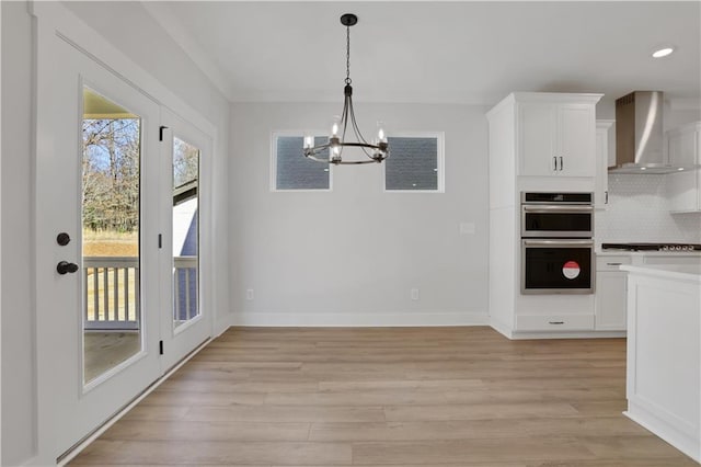 unfurnished dining area featuring light wood-style flooring, baseboards, a notable chandelier, and recessed lighting