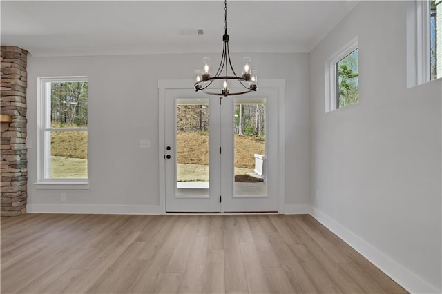 doorway with light wood-style floors, visible vents, a notable chandelier, and baseboards