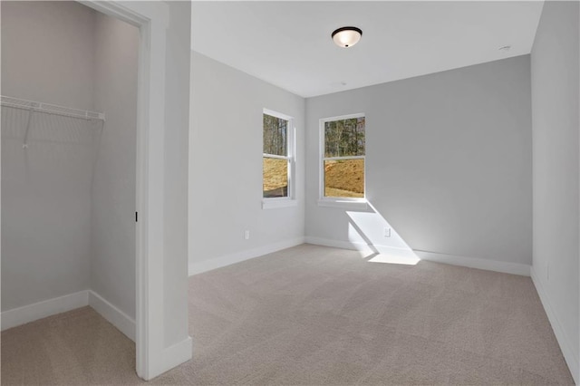 unfurnished bedroom featuring light carpet, baseboards, and a closet