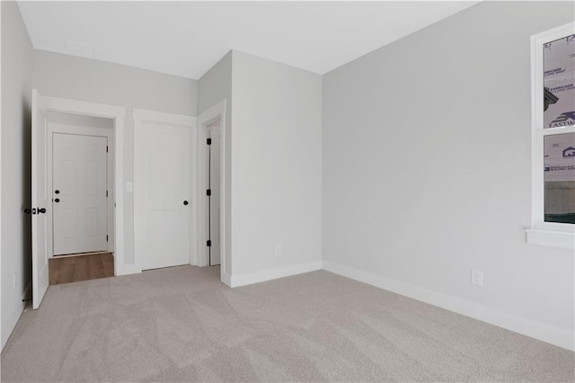 spare room with light carpet and baseboards