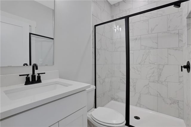 bathroom featuring toilet, a marble finish shower, and vanity