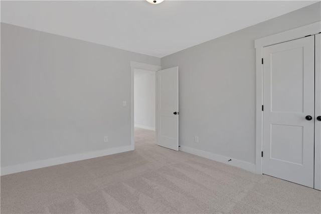 unfurnished room with light colored carpet and baseboards