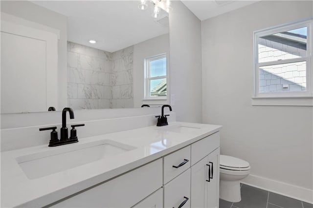 full bathroom with double vanity, tile patterned flooring, a sink, and baseboards